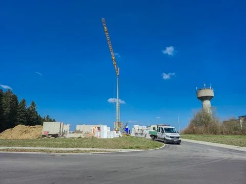 A construction site featuring a prominent crane and a water tower set again.. Stock Photos
