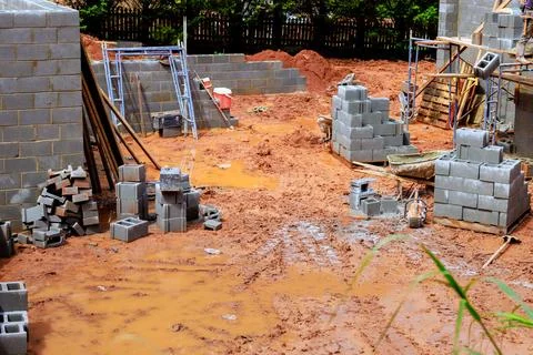 Construction site with gray concrete blocks muddy ground during cloudy day in an Stock Photos