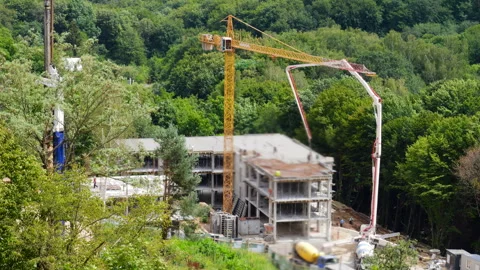 Construction site in a green forest with a yellow tower crane Stock Footage 346375119