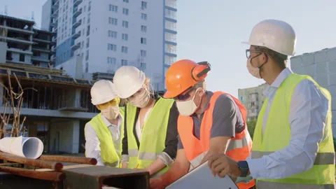 At construction site group of diverse specialists multiracial analyzing the plan Stock Footage 142018461