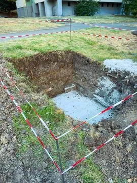 A construction site has a significant hole dug in the ground with a concrete  Stock Photos