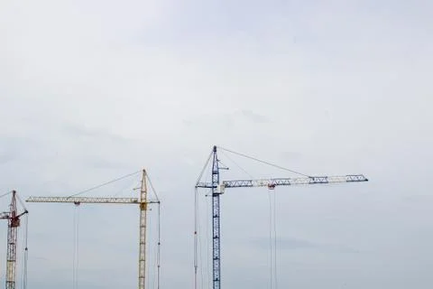 Construction site with high cranes against the blue sky Stock Photos