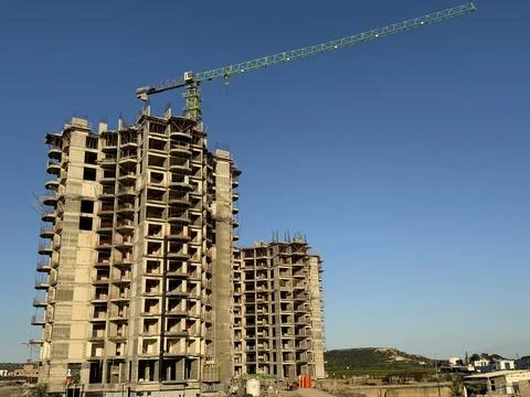 Construction site of a high-rise building with a crane against blue sky Stock Photos