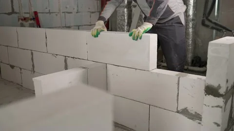 Construction site of a house made of light bricks. The master builds a wall of Video stock 189359209