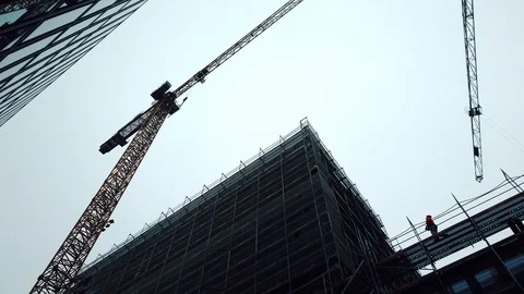 Construction site. It shows two huge cranes lifting construction materials. 4k Stock Footage 102080267