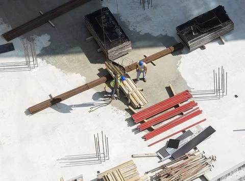 Construction site laborers attaching chains to a load of wooden planks. Foto stock