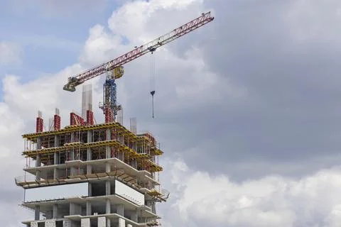 Construction site. A large construction crane against a blue sky builds a hou Stock Photos