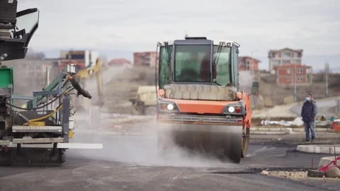 A construction site with a large orange machine spraying water on the road. A Stock Footage 344908845