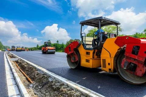 Construction site is laying new asphalt pavement, road construction workers. Stock Photos