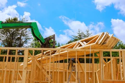 Construction site lift machine lifting wooden beams to build new structure Stock Photos