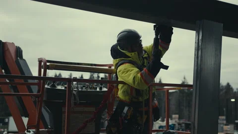 Construction Site: Man puts in fastener on beam Stock Footage 224966547