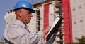 Construction Site Manager Calculates Data Using Adding Machine and Clipboard 4k or 4k+ Resolution