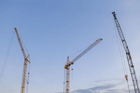 Construction site. Many tower cranes on dusk blue sky background. Constructio Stock Photos