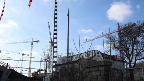 A construction site with multiple cranes, a tall communication tower, and an exc Stock Footage 303908231