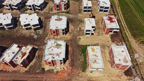 Construction site with multiple unfinished buildings in an open area near a road Stock Footage 337904691