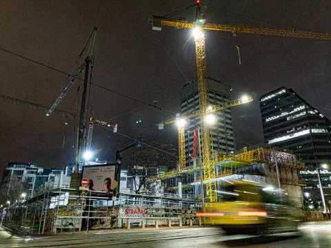 Construction site next to a city boulevard at night with a car passing in front Stock Photos