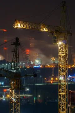 Construction site at night. Cranes working at night over an unfinished house  Stock Photos