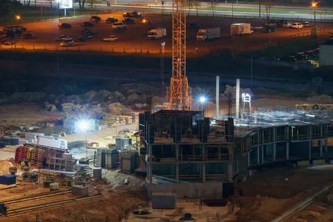 Construction site at night. Cranes working at night over an unfinished house  Stock Photos