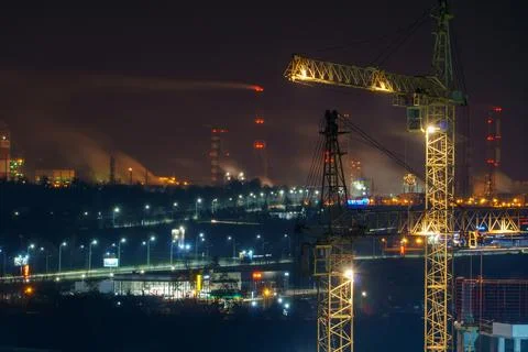 Construction site at night. Cranes working at night over an unfinished house  Stock Photos