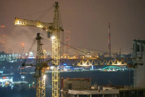 Construction site at night. Cranes working at night over an unfinished house  Stock Photos