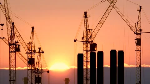 Construction site at orange sunset. Silhouette of high tower cranes works on Stock Footage 160389849
