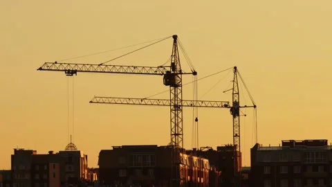 Construction site at orange sunset. Silhouette of high tower cranes works on Stock Footage 160390122