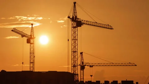 Construction site at orange sunset. Silhouette of high tower cranes works on Stock Footage 160390782
