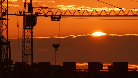 Construction site at orange sunset. Silhouette of high tower cranes works on Stock Footage 160391104