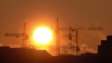 Construction site at orange sunset. Silhouette of high tower cranes works on Stock Footage 160391944