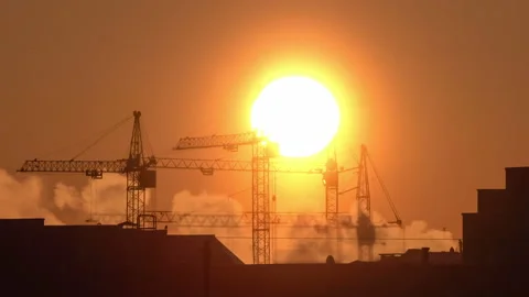 Construction site at orange sunset. Silhouette of high tower cranes works on Stock Footage 160392464