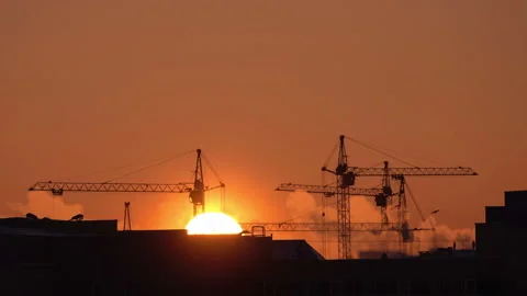 Construction site at orange sunset. Silhouette of high tower cranes works on Stock-Footage 160462519
