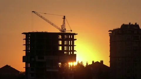 Construction site at orange sunset. Silhouette of high tower cranes works on Stock-Footage 160463124