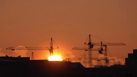 Construction site at orange sunset. Silhouette of high tower cranes works on Stock-Footage 160463147