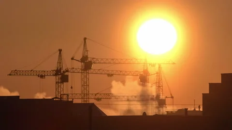 Construction site at orange sunset. Silhouette of high tower cranes works on Stock-Footage 160463409
