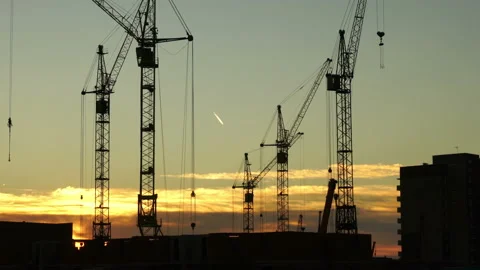 Construction site at orange sunset. Silhouette of high tower cranes works on Stock Footage 160464445