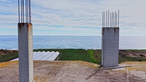 Construction site overlooking the ocean with concrete pillars and farmland Stock Footage 325086632