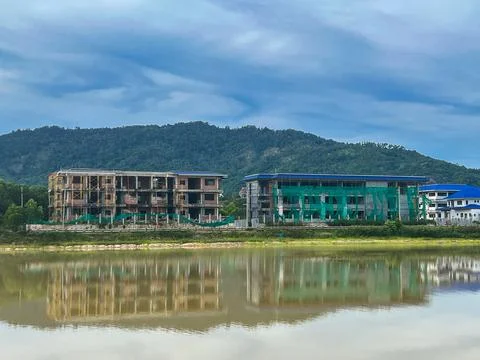 Construction site with partially completed buildings reflected in a lake, s.. Stock Photos