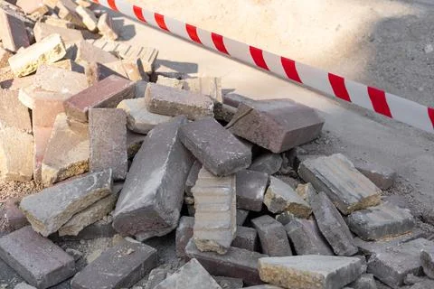 Construction site with a pile of bricks and caution tape marking the area for Stock Photos