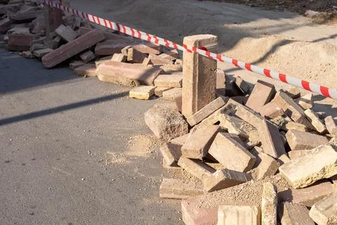 Construction site with a pile of bricks and caution tape marking the area for Stock Photos