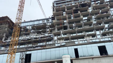 Construction site progress: building a modern skyscraper with cranes and workers Stock Footage 306622608