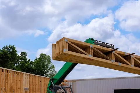 Construction site in progress with heavy machinery lifting wooden beams under Stock Photos