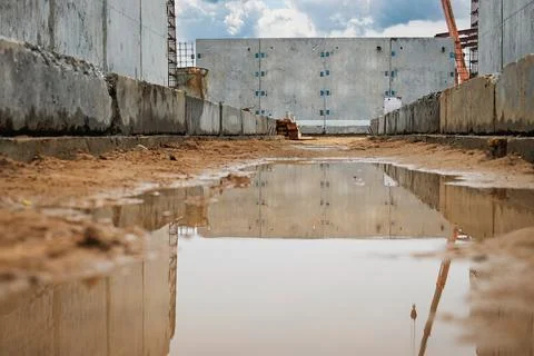 Construction site with puddle reflecting clouds under blue sky during daytime Stock-Fotos