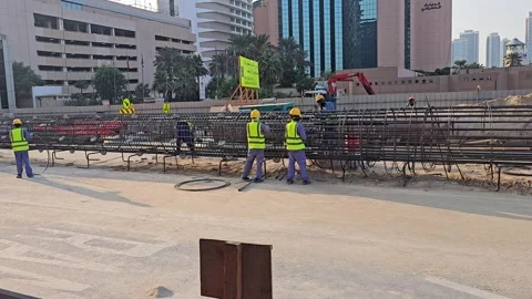 Construction site rebar cage with workers in high-visibility vests under a Stock Footage 322637017