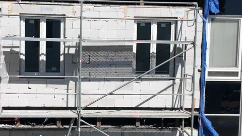 Construction site with scaffolding and windows being installed on a building Stock Footage 335938178