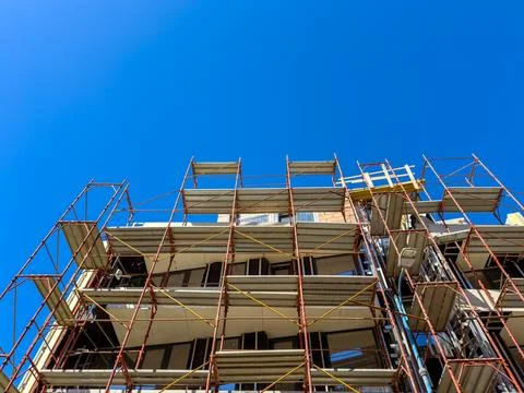 Construction site with scaffolding under a clear blue sky in an urban area Stock Photos