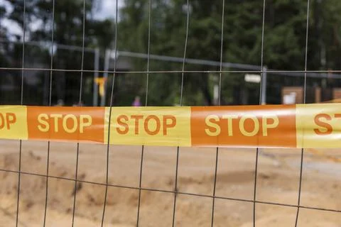 A construction site is secured with bright orange stop tape attached to a f.. Stock Photos