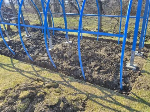 Construction site showcasing a blue structure partially built over a cut soil 库存照片