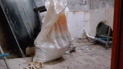 Construction site showing bag of mortar and water pipes being installed Vidéo 297463358