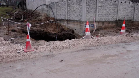 Construction site showing a large sinkhole surrounded by traffic cones and Stock Footage 336064075