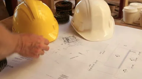 Construction site showing plans and hardhats. Stockbeeldmateriaal 11821206